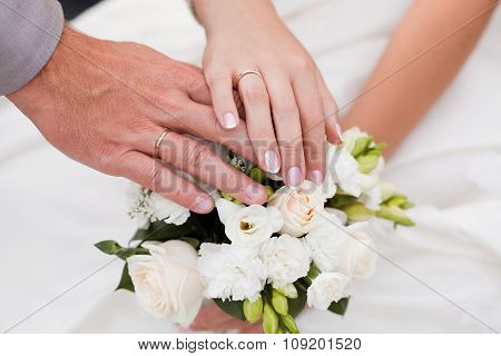 Hands and rings on wedding bouquet