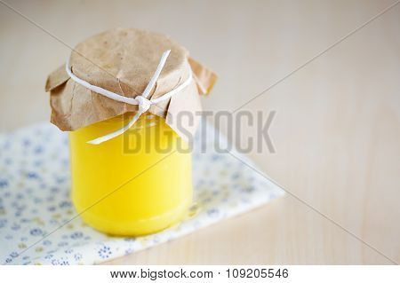 A homemade jar of lemon curd with a lemon and spoon