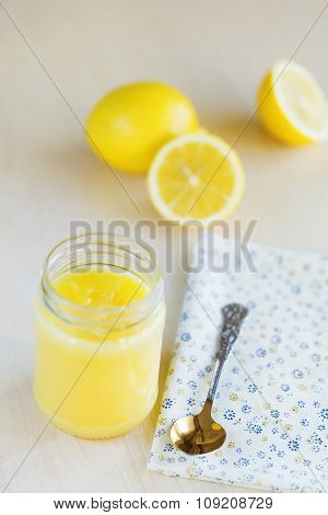 A homemade jar of lemon curd with a lemon and spoon