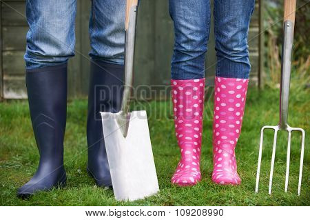 Close Of Couple Gardening Holding Spade And Fork