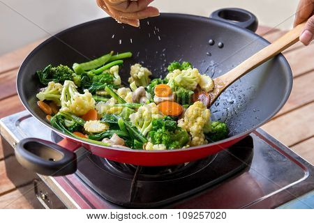 Human Hands Spreading Salt Into Chinese Food Capcay