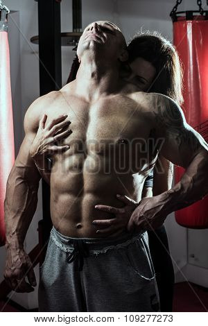 Woman Passionately Embraces Muscular Man In The Gym