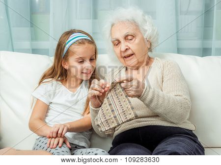 ganddaughter learning to embroider with granny on sofa