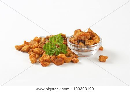 bowl of salty pork greaves on white background