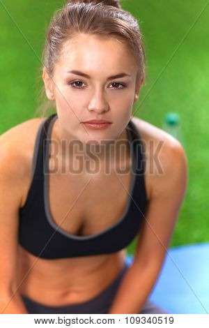 Beautiful young woman relaxing after exerscises on the grass 