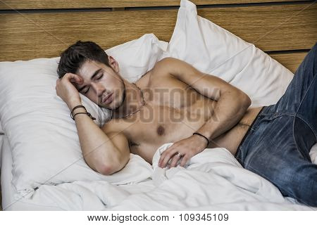 Shirtless sexy male model lying alone on his bed