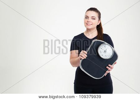 Portrait of a happy fat woman holding weighing machine isolated on a white background