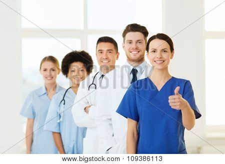 hospital, profession, gesture, people and medicine concept - group of happy doctors showing thumbs up at hospital