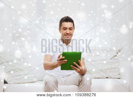 technology, people and lifestyle, distance learning concept - happy man working with tablet pc computer at home over snow effect