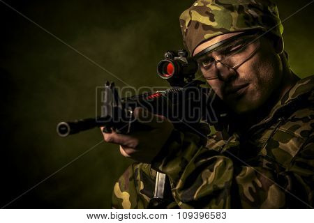 A soldier in war paint looks through the scope of automatic rifles. Military, war. Special forces.