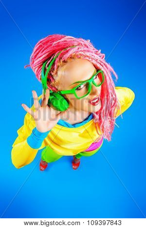 Ultra trendy DJ party girl in bright clothes, headphones and with bright dreadlocks. Disco, party. Show business. Bright fashion.