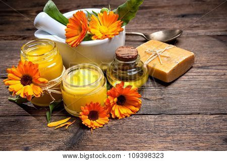 Homemade calendula ointment, soap and oil on wooden table