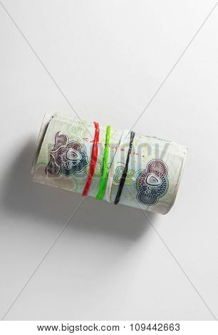 UAE dirham currency. Five hundred dirham notes rolled with rubber bands of national flag colors. A Concept.
