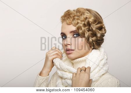portrait of a beautiful young blonde woman on a light background. hair tied in a braid. girl wearing