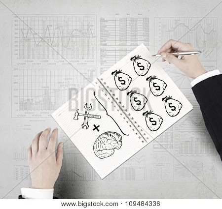 Businessman hands drawing money making formula in notepad