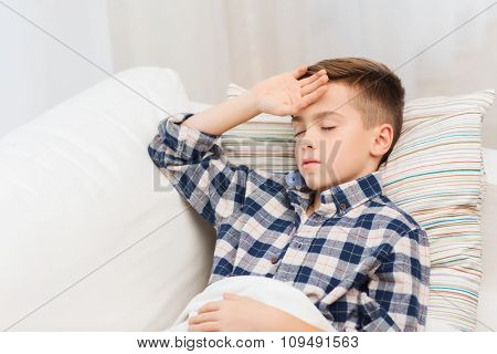 childhood, healthcare, people and medicine concept - ill boy with flu lying in bed at home and suffering from headache