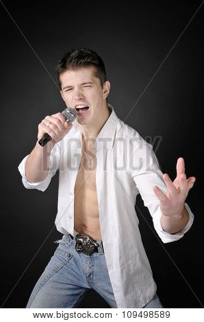 Expressively Man Singing With Microphone On Dark Background.