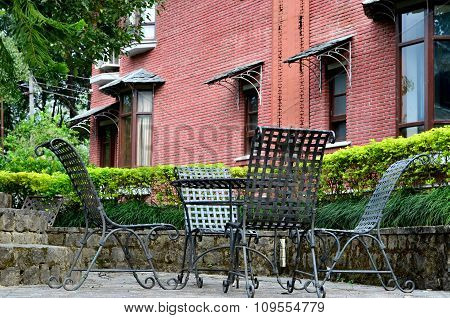 Chairs in a hedged area with brick wall