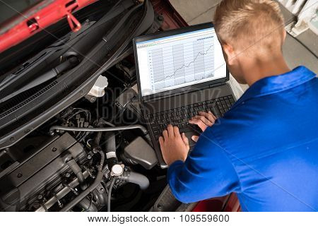 Mechanic Examining Car Engine With Help Of Laptop
