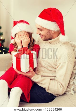 family, christmas, x-mas, winter, happiness and people concept - smiling daughter with closed eyes waiting for a present from fathe