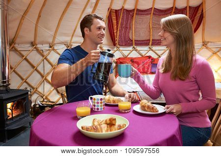 Couple Enjoying Breakfast Whilst Camping In Traditional Yurt