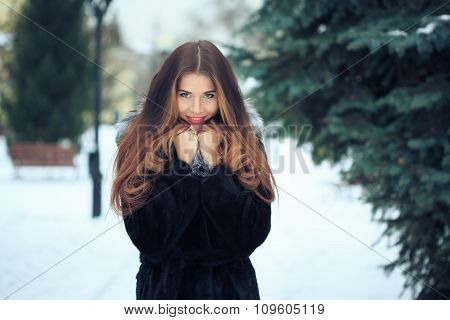 beautiful smiling girl on background of snowy trees. Winter portrait. coat with a hood