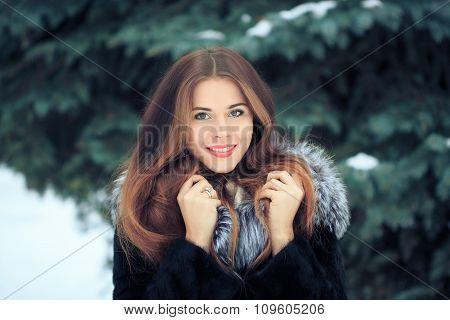 beautiful smiling girl on background of snowy trees. Winter portrait. coat with a hood