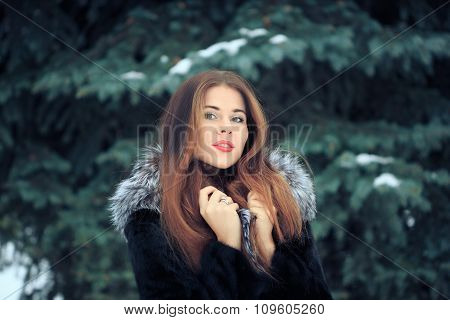 beautiful smiling girl on background of snowy trees. Winter portrait. coat with a hood
