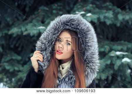 beautiful smiling girl on background of snowy trees. Winter portrait. coat with a hood