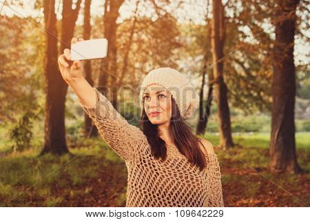 Young woman in park in autumn taking a selfie