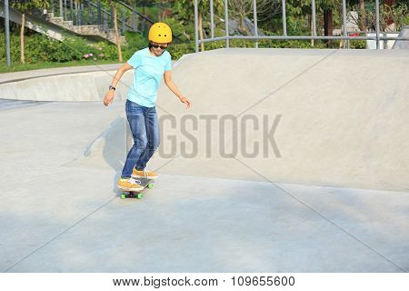 young woman skateboarder skateboarding at skatepark