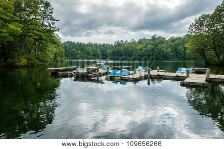 Aluminium bass fishing boat and pedalos at wooden dock in Virginia, America USA