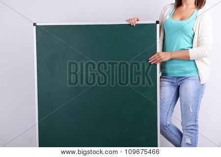 Woman in causal with green blackboard on grey background, close up