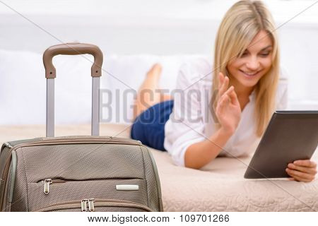 Young woman lying in bed and using her tablet.