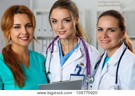 Three Smiling Female Medicine Doctors In Office Looking In Camera Portrait