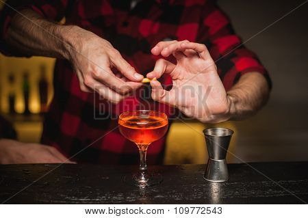 Bartender Is Squeezing Orange Peel Into A Cocktail Glass