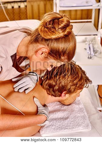 Man  receiving electric massage at beauty salon. Beautician wearing electricity gloves. Top view