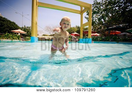 Small Blonde Girl Swims With Joy In Water Of Pool