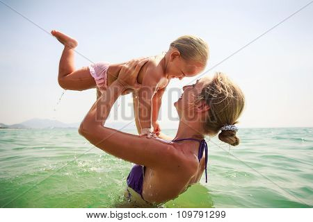 Closeup Side-view Mother Holds Small Daughter Both Smile In Sea