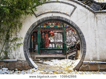 Historic traditional corridor behind a moon gate of Beijing, China in winter with snow