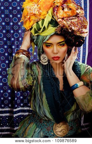 beauty bright woman with creative make up, many shawls on head like cubian, ethno look closeup