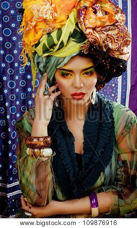 beauty bright woman with creative make up, many shawls on head like cubian, ethno look closeup