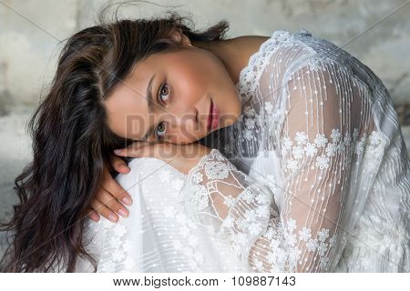Antique edwardian lace dress worn by a beautiful woman against an old wall
