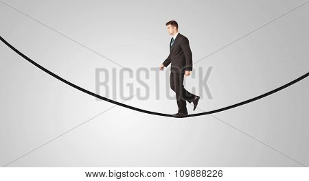 A confident smiling salesman balancing on black wire in clear grey empty space concept