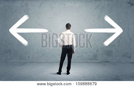 A businessman in doubt, having to shoose between two different choices indicated by arrows pointing in opposite direction concept
