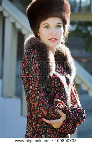 Cheerful Russian beauty in traditional fur Cossack hat and crossed hands
