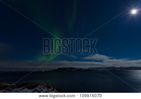 Aurora In The Sky In A Full Moon Night On The Shores Of The Barents Sea
