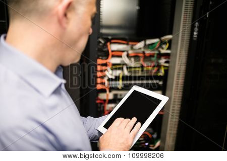 Technician using tablet pc while analysing server at the data centre