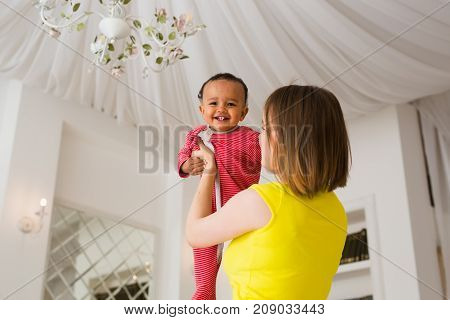 happy family. Mother throws up baby, playing at home.