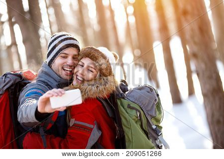 Cheerful hugged couple making winter selfie 
